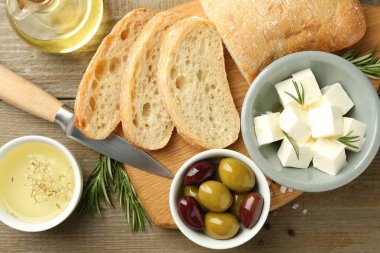 Lezzetli marine edilmiş zeytin, ekmek ve peynir ahşap masada servis ediliyor.