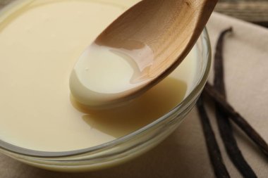 Lezzetli vanilyalı yoğurtlu sütü ahşap masadaki kaşıkla yakın plan çekiyoruz.