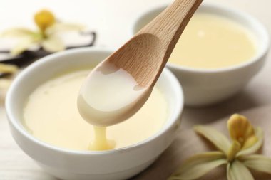 Lezzetli vanilyalı yoğunlaştırılmış sütü beyaz masadaki kaşıktan kaşığa alıp yakın plan çekiyoruz.