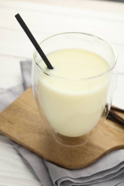 Bardakta vanilyalı süt ve beyaz ahşap masada kapsüller, yakın plan.