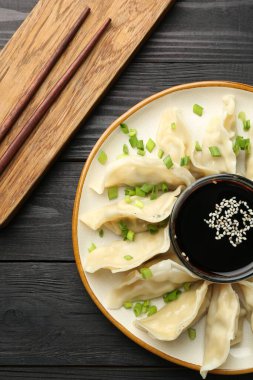 Siyah ahşap masada servis edilen yeşil soğanlı haşlanmış gyoza (hamur tatlısı).