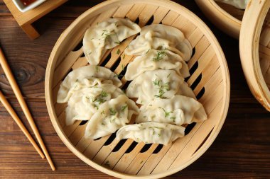 Bambu tenceresinde kaynamış gyoza (hamur tatlısı) ve ahşap masada çubuklar.