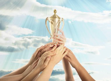 Altın kupa tutan kadın ve gökyüzüne uzanan insanlar.