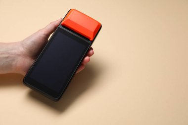 Bej arka planda ödeme terminali olan bir kadın, yakın plan. Metin için boşluk