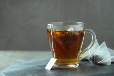 Cam bardakta çay poşeti ve gri masada sıcak içecek. Metin için boşluk