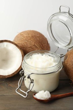 Hindistan cevizleri, pişirme yağı ve kaşık ahşap masada beyaz arka planda