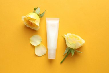 Sarı arka planda dudak merhemi ve güller, düz uzanma