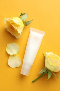 Sarı arka planda dudak merhemi ve güller, düz uzanma