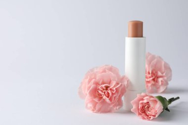 Beyaz arka planda dudak kremi ve Eustoma çiçekleri, yakın plan. Metin için boşluk