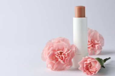 Beyaz arka planda dudak kremi ve Eustoma çiçekleri, yakın plan. Metin için boşluk