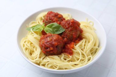 Beyaz fayanslı masada köfteli leziz makarna, yakın plan.