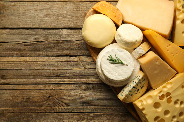 Different types of cheese on wooden table, top view. Space for text