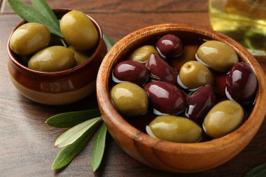 Lezzetli zeytinyağı, yağ ve yapraklar ahşap masada, yakın plan.