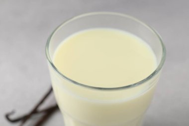 Gri masadaki cam bardakta lezzetli vanilyalı süt, yakın plan.