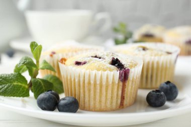 Yaban mersinli lezzetli kekler, pudra şekeri ve nane şekeri beyaz masada, yakın plan.