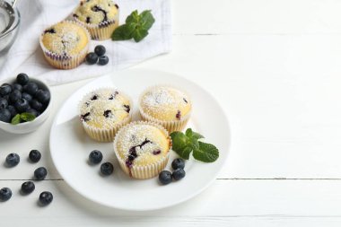 Yaban mersinli lezzetli kekler, pudra şekeri ve beyaz ahşap masada nane şekeri. Metin için boşluk