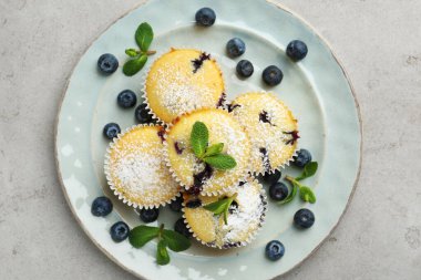 Yaban mersinli lezzetli kekler, pudra şekeri ve nane şekeri gri desenli masa, üst manzara.