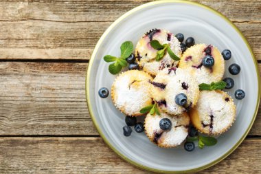 Yaban mersinli lezzetli çörekler, pudra şekeri ve ahşap masa üzerinde nane şekeri, üst manzara. Metin için boşluk