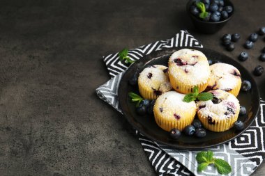 Yaban mersinli lezzetli çörekler, pudra şekeri ve siyah desenli masada nane şekeri, yakın plan. Metin için boşluk