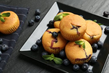 Yaban mersinli lezzetli kekler ve koyu dokulu masada nane şekeri, yakın plan.