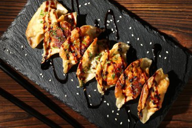 Lezzetli kızarmış gyoza (hamur tatlısı) ve ahşap masa üzerinde çubuklar, üst manzara