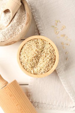 Kahverengi pirinç ve un beyaz ahşap masada, düz yatıyordu.