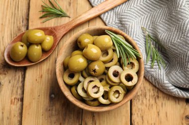 Lezzetli marine edilmiş zeytin halkaları kasede, kaşıkta ve biberiyede ahşap masada, düz yerde.