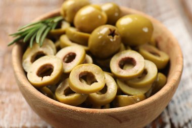 Lezzetli salamura edilmiş zeytin halkaları ve ahşap masada tüm halkalar, yakın plan.
