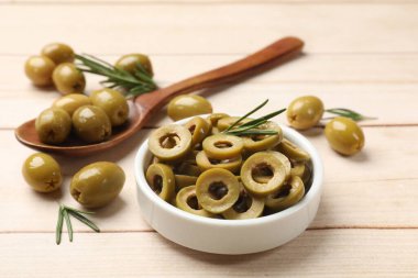 Lezzetli marine edilmiş zeytin halkaları, kaşık dolusu ve biberiye hafif ahşap masada, yakın plan.