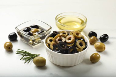 Farklı lezzetlerde marine edilmiş zeytin halkaları, bütün halkalar, biberiye ve yağ ışıklı masada, yakın plan.