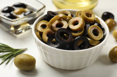 Farklı lezzetlerde marine edilmiş zeytin halkaları ve tüm halkalar ışıklı masada, yakın plan.