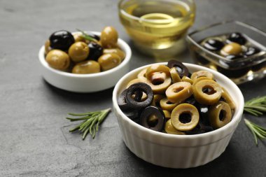 Farklı lezzetlerde marine edilmiş zeytin halkaları, tüm olanlar ve biberiye koyu dokulu masa, yakın çekim