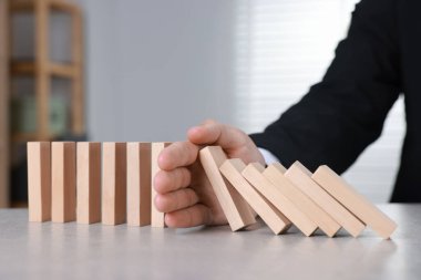 Ahşap blokların masada düşmesini engelleyen adam, yakın plan. Domino etkisi