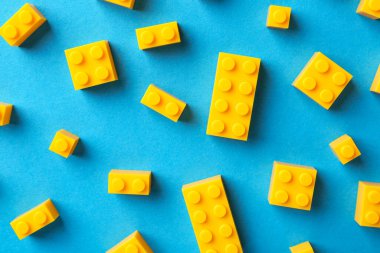 İnşaat oyuncağı. Açık mavi zemin üzerinde birçok sarı yapı taşı düz yatıyordu.