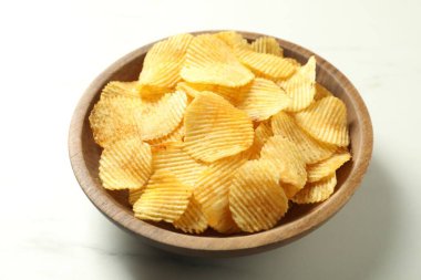 Lezzetli patates cipsleri beyaz mermer masada, yakın plan.