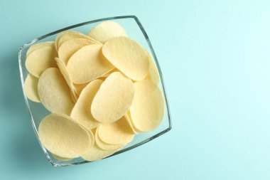 Açık mavi arka planda leziz patates cipsleri, üst manzara. Metin için boşluk
