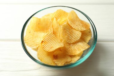 Beyaz ahşap masada patates cipsi, yakın plan.