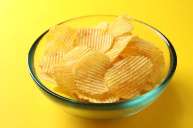 Sarı arka planda lezzetli patates cipsi, yakın plan.