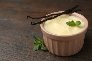 Lezzetli vanilyalı puding, nane ve kapsüller ahşap masada, yakın plan. Metin için boşluk