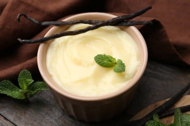 Lezzetli vanilyalı puding, nane ve kapsüller ahşap masada, yakın plan.