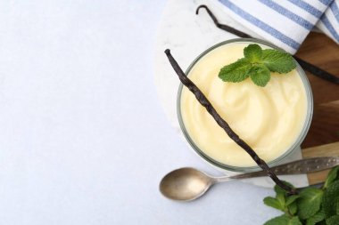 Lezzetli vanilyalı puding, nane ve kapsüller beyaz masada, düz konum. Metin için boşluk