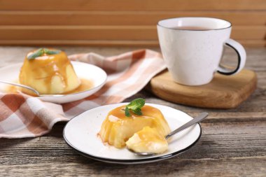 Karamel soslu lezzetli puding ve ahşap masada servis edilen nane.