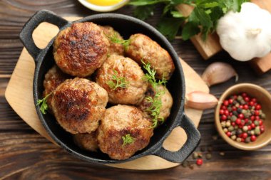 Lezzetli köfteler, kızartma tavasında dereotu ve ahşap masada biber, düz uzanmış.