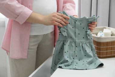 Evde bebek elbiseli bir kadın var, yakın plan.