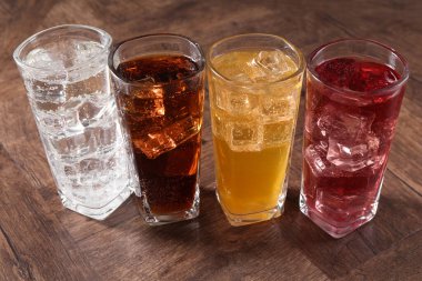 Farklı aromalı soda ve ahşap masada buz küpleri.