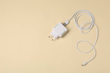 USB güç adaptörü ve kabloyu bej arka planda şarj et, düz konum. Metin için boşluk