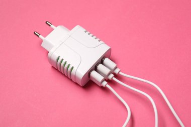 Pembe arka planda şarj kabloları olan USB güç adaptörü, kapat