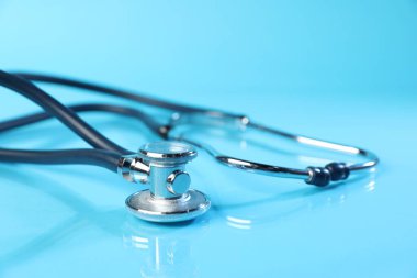 Açık mavi arka planda steteskop, yakın plan. Tıbbi araç