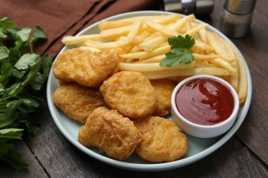 Lezzetli tavuk nugget ve ahşap masada soslu patates kızartması, yakın plan.