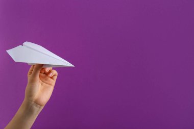 Mor arka planda beyaz kağıt uçaklı kadın, yakın plan. Metin için boşluk
